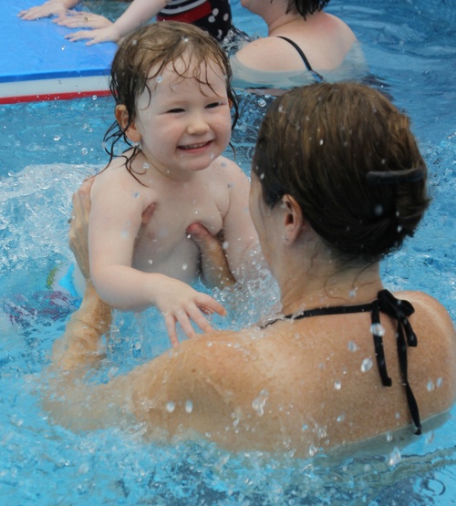 child learning to swim with mum