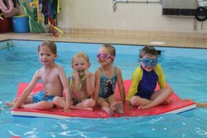 children swimming on mat